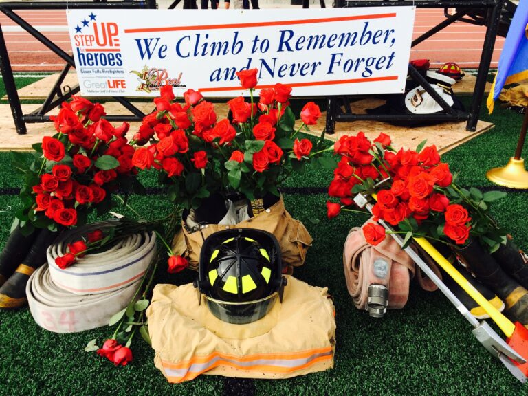 A photo of a fireman's hat by a bed of roses.